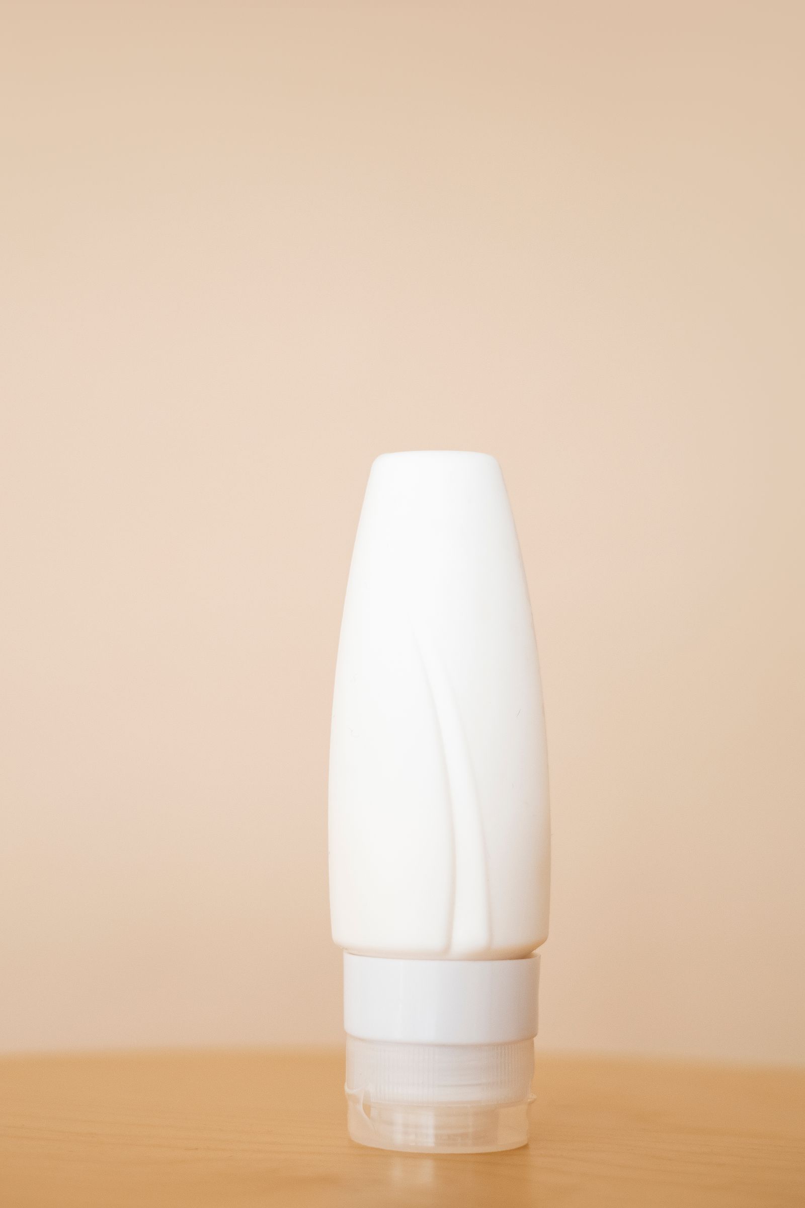 Minimalist product presentation of a white cosmetic bottle